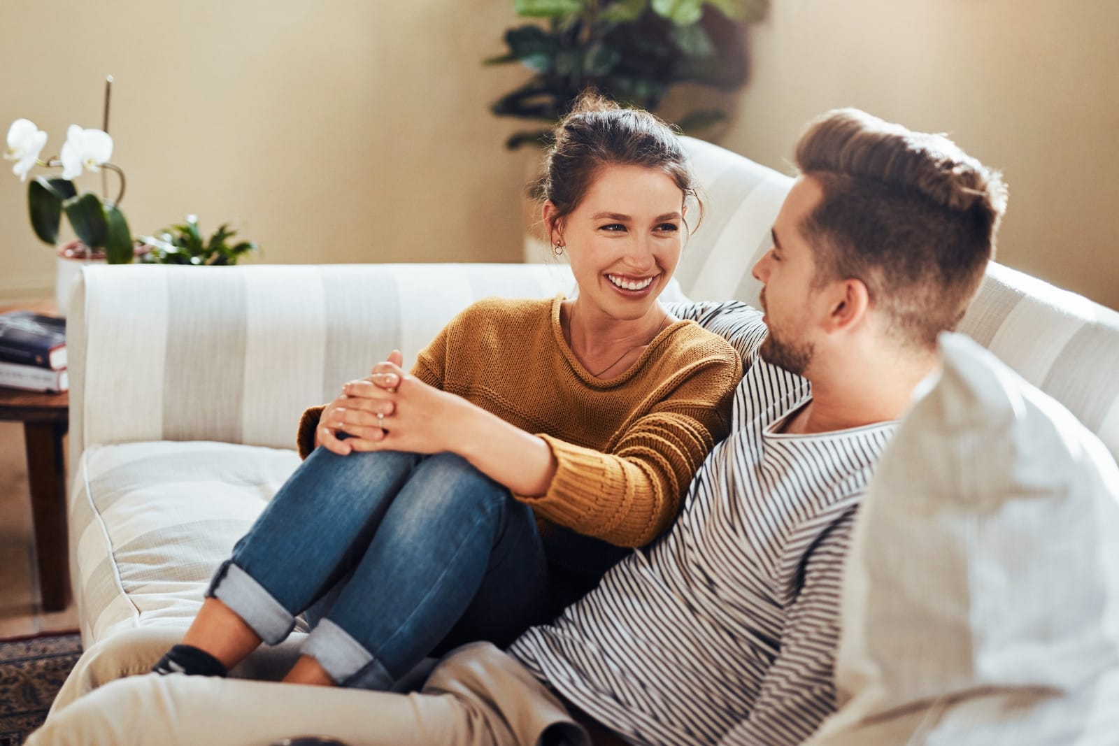A man and a woman sitting closely on a couch, engaged in a happy conversation. Image @Canva